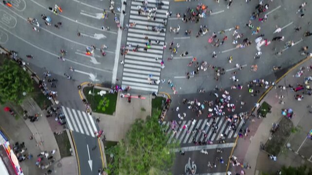 Guadalajara, Mexico - June 13 2026: Top-down drone shot capturing a vibrant Pride parade moving along a city street, showcasing participants, rainbow flags, and urban environment.