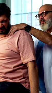 Indian physiotherapist treating young patient for neck and shoulder pain during physical therapy session as experienced male therapist provides manual treatment inside modern Indian clinic