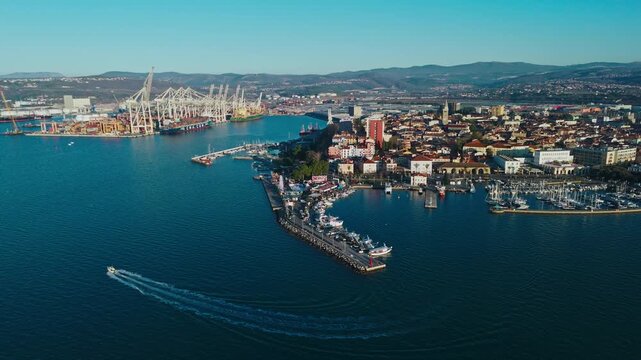Koper features a bustling waterfront, historic buildings, and a busy marina on the Adriatic Sea. The landscape displays Mediterranean charm.