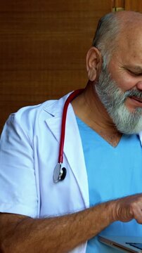 Indian doctor patient discuss case while walking in porch as senior male physician reviews medical file on laptop with patient during outdoor consultation near modern clinic healthcare visit
