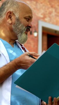 Indian doctor patient discuss case outdoors in natural greenery as senior male physician reviews medical report on laptop or looking at case file with patient during open air healthcare consultation