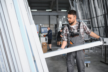 Worker carrying pvc window profile in factory workshop