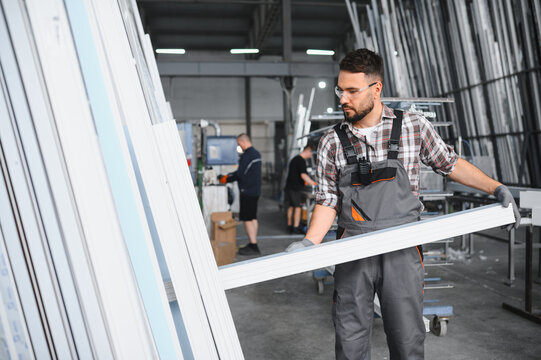 Worker carrying pvc window profile in factory workshop