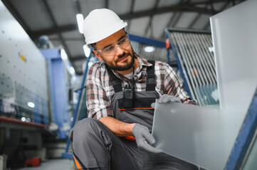 Fototapeta na wymiar Worker inspecting pvc window glass in factory