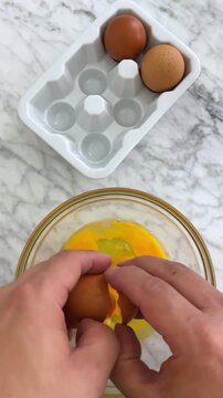 tap the egg on a hard surface to create an initial crack, followed by using the thumbs to gently pull the shell apart and break the inner membrane 