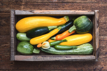 Fresh zucchini arranged in crate on wooden surface, organic vegetables composition, seasonal harvest concept. Green and yellow squash top view, natural texture, healthy food © Ivan Kmit