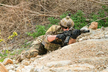 Naklejka premium The sacrificing soldiers lie prostrate on the ground camouflaged behind rocks preparing fire upon the enemy on the ground in a ready to attack stance. 