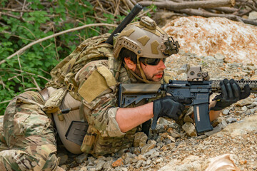 Naklejka premium The sacrificing soldiers lie prostrate on the ground camouflaged behind rocks preparing fire upon the enemy on the ground in a ready to attack stance. 