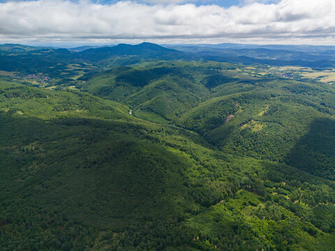 Aerial view of the Bohunicky Rohac peak in the Stiavnicke Vrchy mountains with dense green forests and rolling hills under a cloudy sky in Bohunice, Nitra Region, Slovakia.