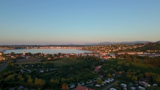 Take a look at Urrugne bay from an aerial view showcasing the houses, water and land at sunset without distractions