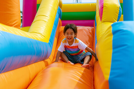 AI-generated images of children having fun in an inflatable bounce house. Developmental benefits: Climbing and jumping in the bounce house help develop children's gross motor skills and balance.