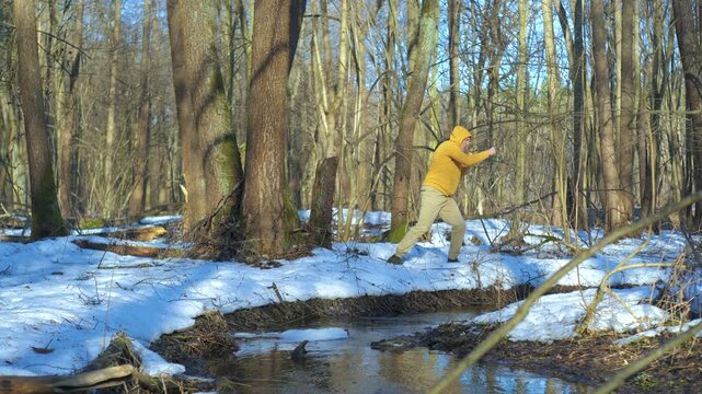 Man shadow boxing outdoors in snowy spring forest near flowing stream, functional cardio training improving speed coordination and endurance