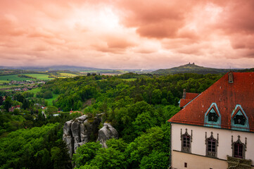 Obraz premium View from the tower of Hruba Skala Castle over the landscape of Bohemian Paradise (Cesky raj), Czech Republic, with silhouette of Trosky Castle ruin in the distance under dramatic soft sky panorama