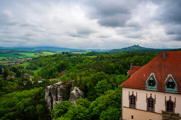 Fototapeta premium View from the tower of Hruba Skala Castle over the landscape of Bohemian Paradise (Cesky raj), Czech Republic, with silhouette of Trosky Castle ruin in the distance under dramatic soft sky panorama