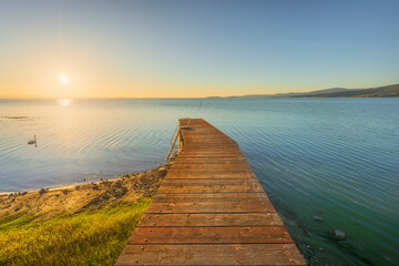 Obraz premium Wooden Pier on Lake Trasimeno at Sunset with Swan