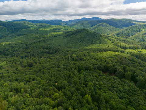 Aerial view of the lush green forests and rolling hills of Bohunicky Rohac in the Stiavnicke Vrchy mountains under a cloudy sky in Bohunice, Nitra Region, Slovakia.