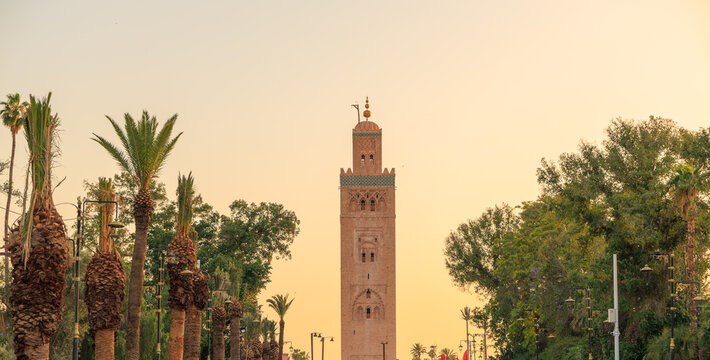 the Koutoubia tower against orange sunset sky with palm trees along side, text space, Marrakech, Morocco