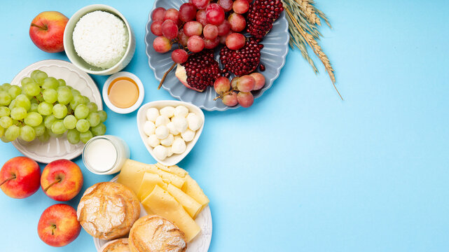 Jewish Shavuot Holiday Card. Dairy Products, Grapes, Cheese, Bread, Milk on Blue Background.