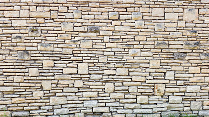 Obraz premium Textured Beige Stone Wall with Irregular Brick Pattern