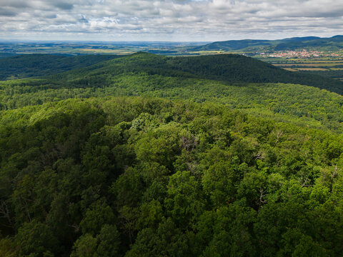 Aerial view of the lush green forests of Bohunicky Rohac in the Stiavnicke Vrchy mountains with rolling hills and a distant village in Bohunice, Nitra Region, Slovakia.