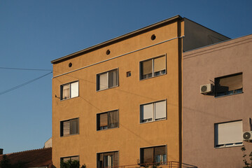 Fototapeta premium Yellow building facade with multiple windows in an urban residential area during daytime, showcasing architecture.