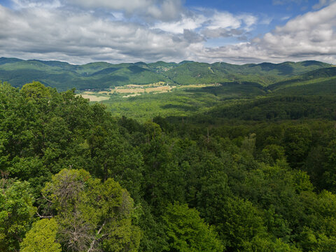 Aerial view of Bohunicky Rohac in Stiavnicke Vrchy with dense green forest canopy and rolling hills under a cloudy sky Bohunice, Nitra Region, Slovakia.