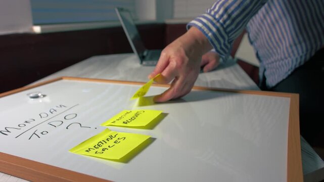 Woman with Monday morning schedule with sticky notes on whiteboard