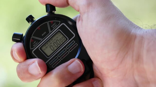 A close-up of hands holding a digital stopwatch, emphasizing precision, timing, and the start of a race or workout.