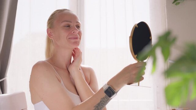 Smiling woman admiring her reflection in mirror, feeling confident and happy with her appearance during peaceful self care moment at home.Self love , confidence , body positivity concept