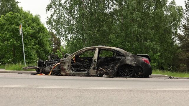 wrecked automobile with extensive fire damage parked on a roadside illustrating the impact of technical issues and vehicle fire emergencies