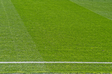 Naklejka premium Detailed view of fresh green grass on a stadium or sports pitch with a crisp white boundary line and mowed stripes