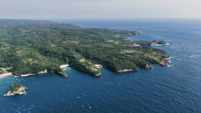 Wide aerial view of Nusa Penida coastline with cliffs coves and turquoise ocean Bali