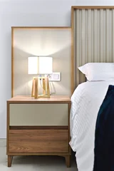 A stylish bedroom interior with contemporary bedside table, wooden lamp and white bedding. Hotel accommodation, interior design, and home decor concepts. © Alex Tihonov