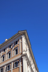 Fototapeta premium Historic Corner Building Against Clear Blue Sky in Rome, Italy