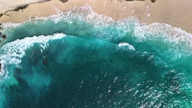 Aerial drone view of turquoise ocean waves lapping sandy beach shore Nusa Penida Bali