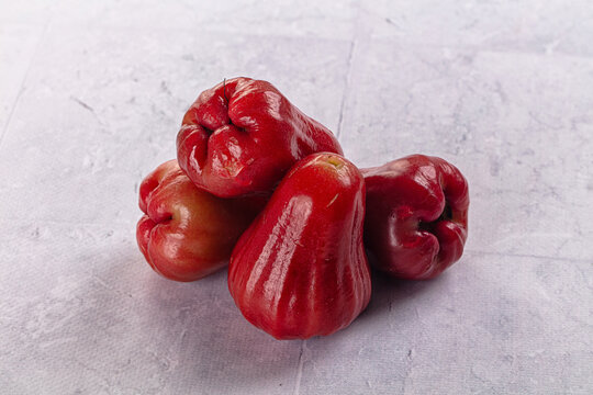 Red wax apples arranged on textured white surface