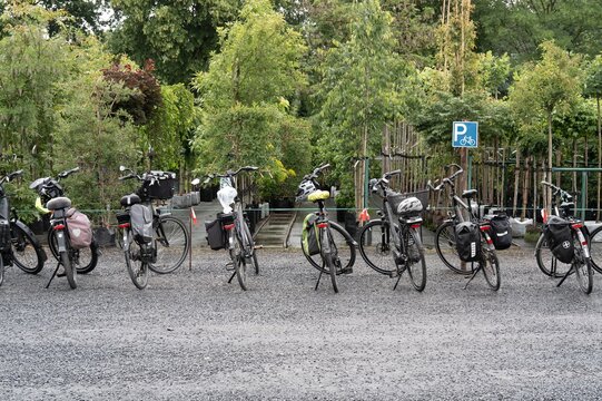Bicycles parked in a green area near a bike parking sign on a gravel surface during daytime