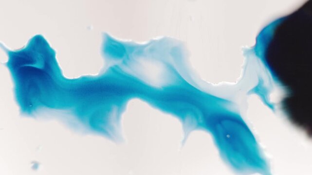 Close up of blue watercolour mixing on a glass. Artist draws with a brush, liquid analog effects for background with copy space for text in center. 