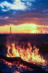 Obraz premium A campfire lit up a vast field as the sun sets behind it vertical frame