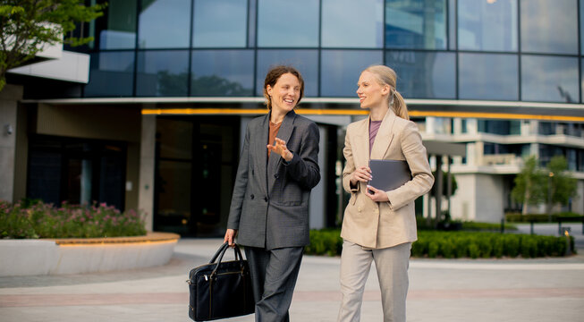 Businesswomen walk outside office building in city during daytime