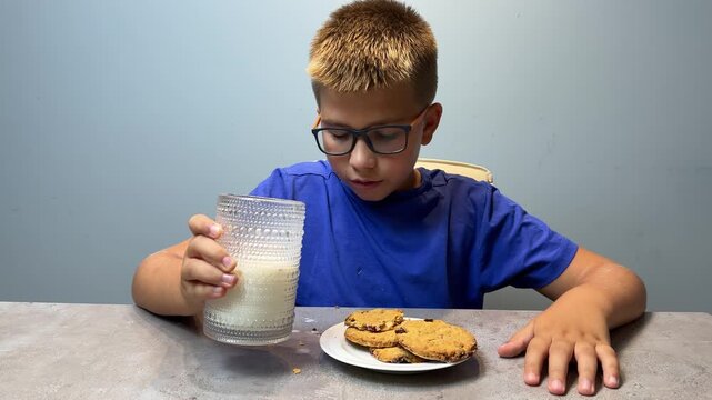 Boy in Glasses Eating Cookies at Table