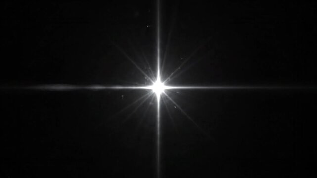 Bright white starburst light flash glowing on black background.
