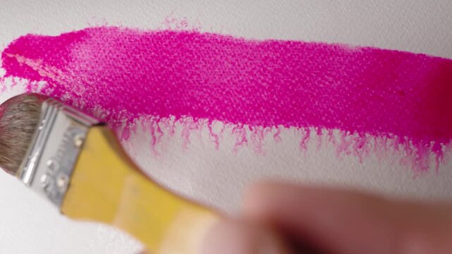 Close up of pink watercolour drawing paints on paper. Artist draws with a brush, liquid analog effects for background with copy space for text in center. 