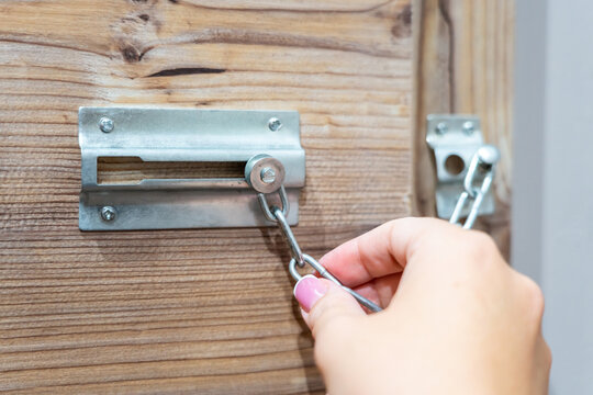 Close up of hand holding security door chain on wooden door