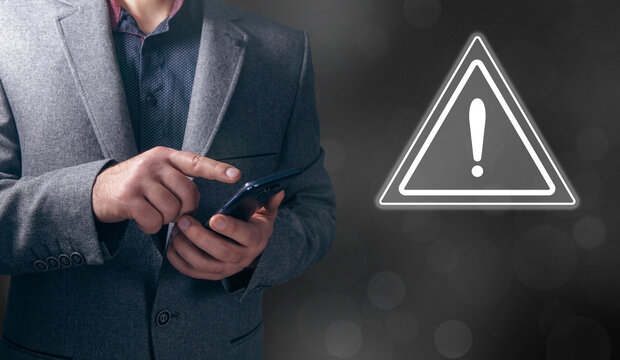 A young man clicks on a virtual screen with a warning sign.