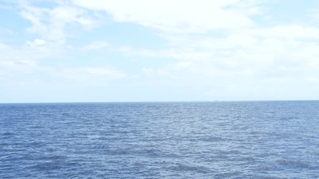 4K static shot of open ocean horizon with ripples and cloudy blue sky