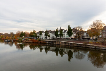 Fototapeta premium Scenic view of the Meuse river embankment with historic buildings reflected in water in Maastricht