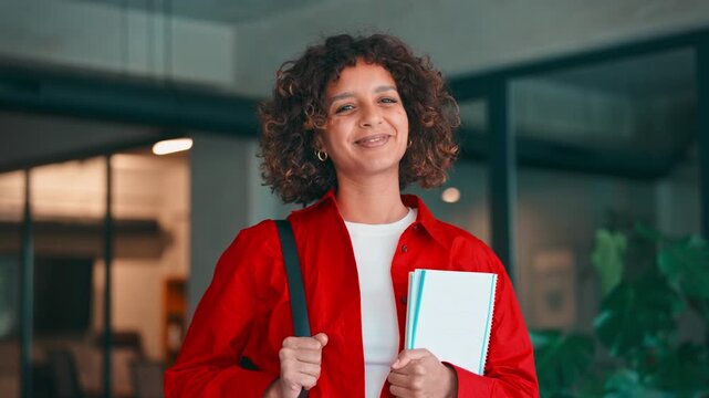 Female multicultural teenager student girl holding notebooks, backpack indoors smiling at modern school or university campus. Young muslim or indian woman smiling at camera. Education and motivation