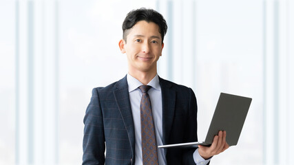 Fototapeta premium ノートパソコンを持つ笑顔の男性・ビジネスマン, Smiling Businessman Holding a Laptop