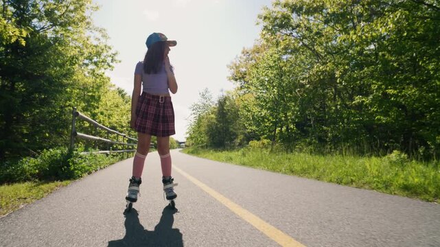A girl in a cute skirt and cap glides effortlessly on her skates under the warm sun, surrounded by vibrant trees and a peaceful path. Pure bliss in nature.